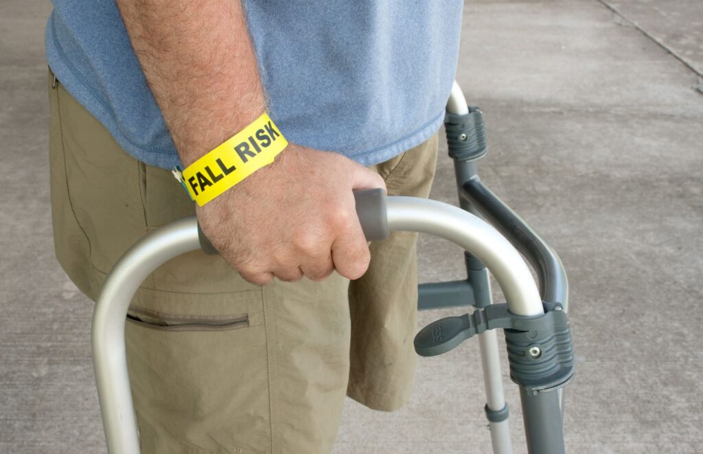 Patient walking with walker. Yellow "Fall Risk" wrist band. 