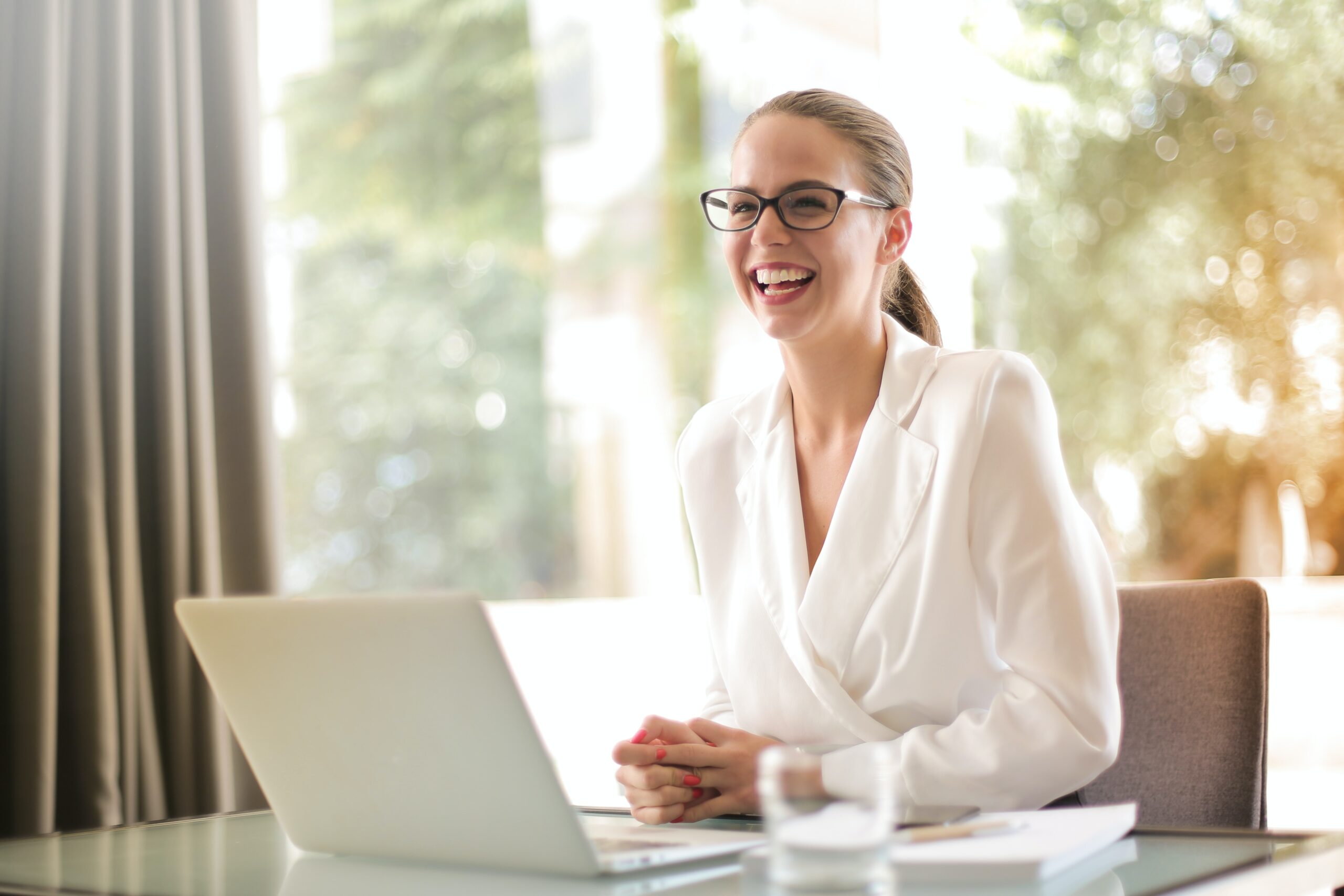 Happy manager sitting at a desk smiling with laptop open. It appears that she is very happy with the results of her employee's webFCE Occupational Testing.