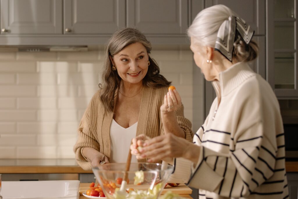 Two women making a salad and enjoying each others company. They're looking to improve their overall health as a part of their fall prevention efforts.
